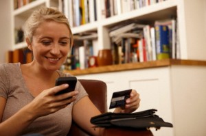 Woman using smartphone, holding credit card